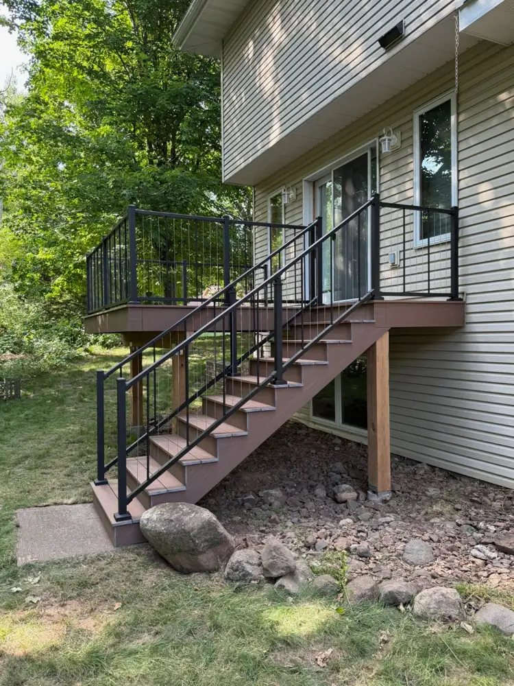 Composite deck stairs with black aluminum railings leading up to a raised deck