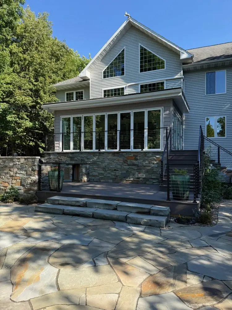 Composite deck with cable railings, stone steps and a flagstone patio
