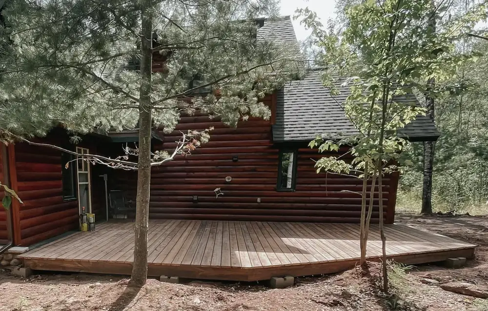 Freshly built ground-level deck wrapping a log cabin