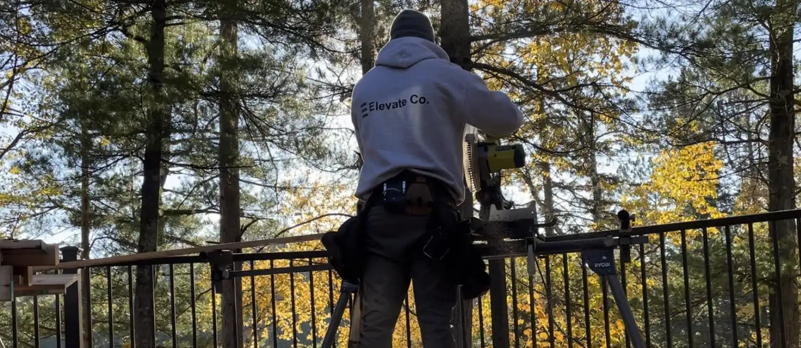 Torin installing a railing on a deck surrounded by pine trees
