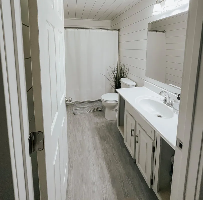 Bathroom with shiplap walls, white vanity and plank flooring